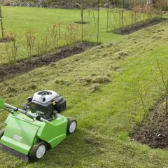 Wertykulacja i aeracja trawnika w ogrodzie. Zielony wertykulator usuwa filc i mech, przygotowując glebę do lepszego napowietrzenia.