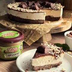 Ciasto Kinder Bueno z mascarpone, udekorowane orzechami i czekoladkami. Obok słoik pasty z orzechów laskowych.