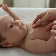 Delikatna pielęgnacja 2 miesięcznego dziecka. Kremowanie jego skóry to chwila bliskości i troski.