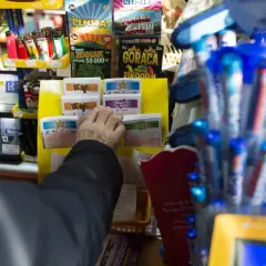 Dłoń wybierająca zdrapki z gabloty z grami losowymi.