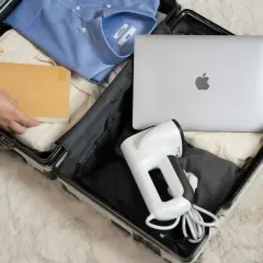 Pakowanie bagażu rejestrowanego: laptop, koszula, książka i podręczny parownica.