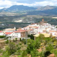Vista panorámica de las menas Almería, un pueblo blanco en una ladera con montañas al fondo.