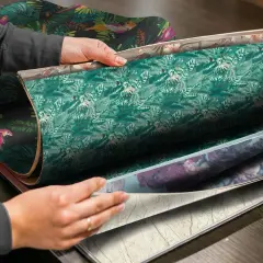 Händer bläddrar i tapetprover med djungelmotiv och blommor. Perfekt för att tapetsera trapphus med en tropisk känsla.