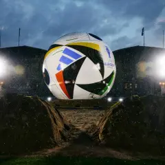 Gigantyczna piłka mistrzostw europy, symbol nadchodzącego turnieju, lśni w deszczu przed stadionem.