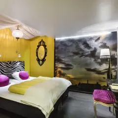 Ett mysigt eget rum på vandrarhem i Stockholm med zebra-mönstrat sänggavel, gul vägg och dramatisk molnhimmel som fondtapet.