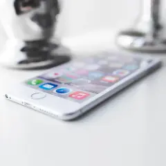 Biały iPhone z ikonami aplikacji na ekranie. Dowiedz się, jak wyczyścić telefon ze śmieci, by działał szybciej.