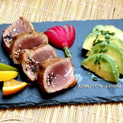 Tataki de bonito sellado con sésamo, acompañado de aguacate, rábano y cítricos.