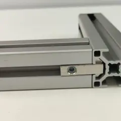 Dwa połączone profile aluminiowe konstrukcyjne tworzą kąt prosty. Widać element łączący z nakrętką.