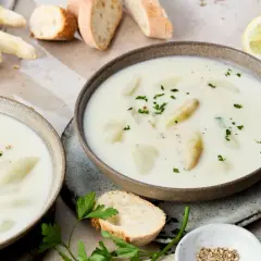 Cremige Spargelsuppe aus Spargelschalen, garniert mit Petersilie. Dazu Baguette und Zitronenspalten.