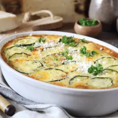 Szybka i prosta zapiekanka z cukinii, udekorowana natką pietruszki i parmezanem, gotowa do podania.