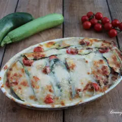 Parmigiana di zucchine non fritte, con pomodorini e formaggio filante, pronta per essere gustata.
