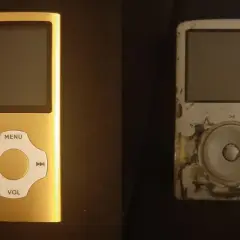 A new gold mp3 player sits next to a worn, scratched silver one.