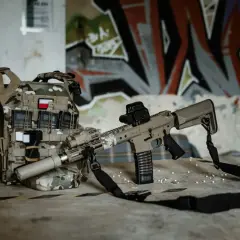 Kamizelka taktyczna z polską flagą i karabin ASG g3, gotowe do akcji na tle graffiti.