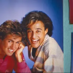 George Michael i Andrew Ridgeley z Wham! uśmiechają się radośnie. Ich klasyczne george michael utwory wciąż brzmią w naszych sercach.