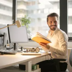Ein Mann im Büro liest ein Buch. BWL: Was macht man da? Er lernt, wie man erfolgreich ist.