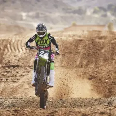 Motocrossowy zawodnik w stroju z logo Fox, jak prawdziwy fox titan, pędzi po piaszczystym torze, wzbijając tumany kurzu.