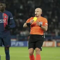 Sędzia pokazuje żółtą kartkę piłkarzowi PSG.