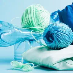 Bouteille en plastique bleue, pelotes de fil vert et bleu, et tissu bleu et vert pâle. Le fil est fait de polyester fiber, prêt à être recyclé.