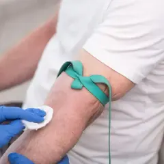 Ręka pacjenta z opaską uciskową i wacikiem przygotowywana do pobrania krwi. Badanie hbs.