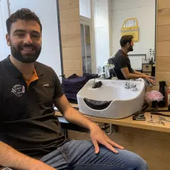 Le tonsor souriant, barbier dans son salon, entouré de ses outils de coiffure.