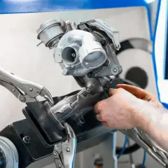 Mechanik pracuje nad turbosprężarką, przygotowując ją do czyszczenia n75. Urządzenie jest zamocowane w imadle.