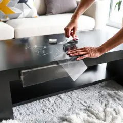 Une personne relooker table basse avec carrelage adhésif effet marbre. Le résultat est élégant et moderne.