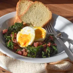 Plato de espinacas con jamón, huevo duro y tostadas. Un desayuno o almuerzo saludable y delicioso.