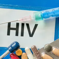 Strzykawka, tabletki i stetoskop na tle napisu HIV.