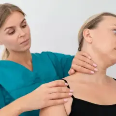 Fizjoterapeuta bada szyję pacjentki, oceniając potencjalne objawy chorobowe kręgosłupa szyjnego.