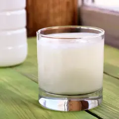 Szklanka z kefirem na zielonym stole. Czy kefir jest pasteryzowany? To pytanie nurtuje wielu miłośników tego napoju.