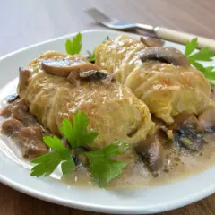 Gołąbki z kaszą gryczaną i pieczarkami, jak u Ani Gotuje, w kremowym sosie, ozdobione natką pietruszki.