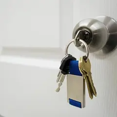 Un trousseau de clés pend à une poignée de porte blanche. J'espère que le serrurier n'a pas pratiqué un serrurier prix abusif pour cette simple serrure.