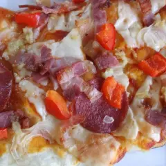 Pikantna pizza diavola z salami, boczkiem i papryką, gorąca i apetyczna.