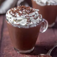 Cioccolata calda con acqua e cacao, guarnita con panna montata e codette di cioccolato. Un comfort food perfetto per riscaldarsi.