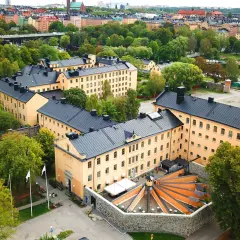 Långholmen vandrarhem, en före detta fängelsebyggnad i Stockholm, omgiven av grönskande träd och med en vacker utsikt över vattnet.