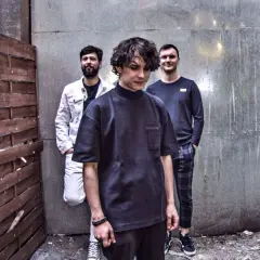 Trzech mężczyzn w miejskiej scenerii. Jeden w czarnym t-shircie, drugi w białej kurtce, trzeci w granatowej bluzie. Jakby czekali na sygnał, może na drugi dym, by rozpocząć grę w the cassino.