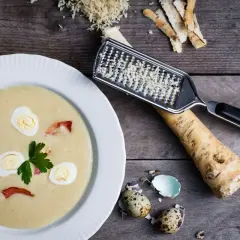 Kremowa zupa chrzanowa z jajkiem i boczkiem, obok świeży chrzan i tarka. Idealny przepis na Wielkanoc.