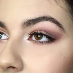 Occhi marroni con ombretto rosa e marrone, ciglia lunghe e eyeliner. Un esempio di come truccare gli occhi per un look sofisticato.