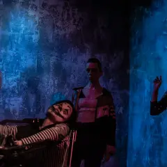 Scena z teatru Barakah. Aktor w wózku, klaun z makijażem, kobieta w cekinowej sukience i mężczyzna w białej koszuli.