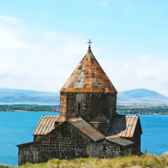 Kamienny klasztor na wzgórzu nad jeziorem, z daleka widać góry i miasto. To piękny przykład architektury, którą tworzyli ormianie.