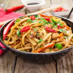 Pyszny makaron chow mein z kurczakiem, papryką i chili, posypany świeżą pietruszką.