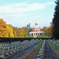 Jesienne liście pokrywają alejki największego cmentarza w Polsce. W oddali widać zabytkową kaplicę.