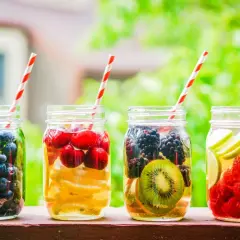 Quattro barattoli con acqua detox: mirtilli, ciliegie e limone, more e kiwi, lamponi e lime.