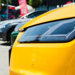 Gros plan sur le phare d'une voiture jaune vif, avec d'autres voitures en arrière-plan. Pensez à la résiliation de votre assurance auto pour ce bolide.