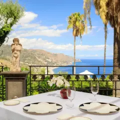 Tavola apparecchiata con vista mare a Taormina, un'esperienza tra i migliori ristoranti.
