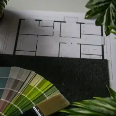 Floor plan, paint swatches, and a brush lay on a surface, ready for your next remodel.