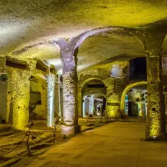 Un viaggio nelle catacombe di San Gennaro, un luogo suggestivo con tombe scavate nella roccia e colonne antiche.