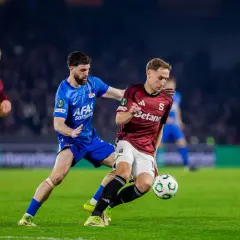 Piłkarze w akcji podczas meczu sparta praga: rozgrywki. Jeden z nich w bordowej koszulce walczy o piłkę z rywalem w niebieskim stroju.