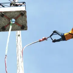 Człowiek w żółtej koszulce skacze na bungee. Zastanawiasz się, ile kosztuje skok na bungee? To niezapomniane przeżycie!