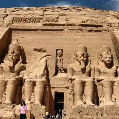 Gigantescas estatuas de Ramsés II flanquean la entrada del templo de Abu Simbel, Egipto. Un pequeño grupo de turistas admira la magnificencia de esta maravilla antigua.